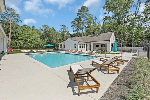 a view of a swimming pool and lounge chairs in back of the house