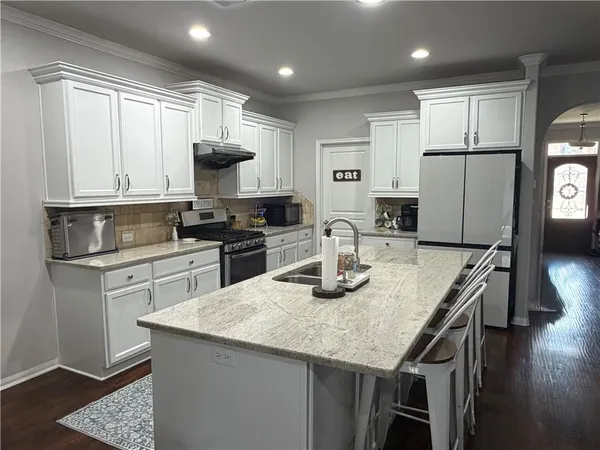 a kitchen with stainless steel appliances granite countertop a sink a stove a microwave and a refrigerator