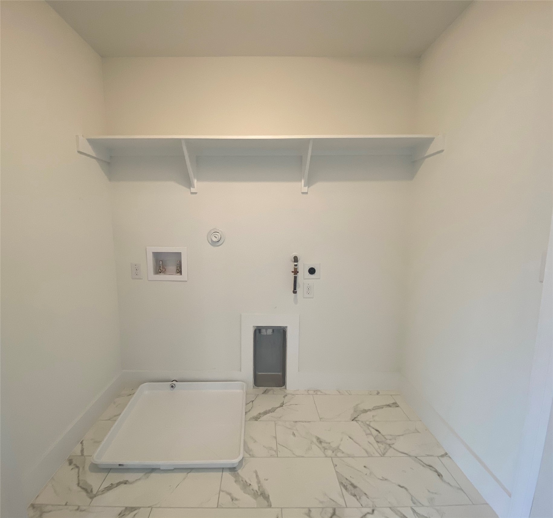 1916 Webberville Road, Unit B Austin, TX 78721 - Photo 23 of 25 Bright utility space featuring marble-look tile flooring, a white wall shelf, and appliance hookups