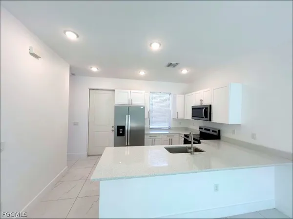 a large white kitchen with kitchen island granite countertop a sink a stove and a refrigerator