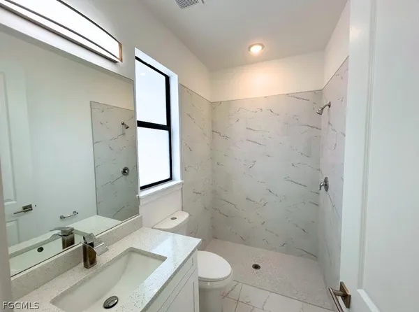 a bathroom with a sink a toilet and shower