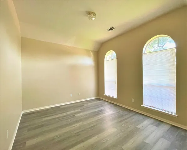 a view of an empty room with wooden floor and windows