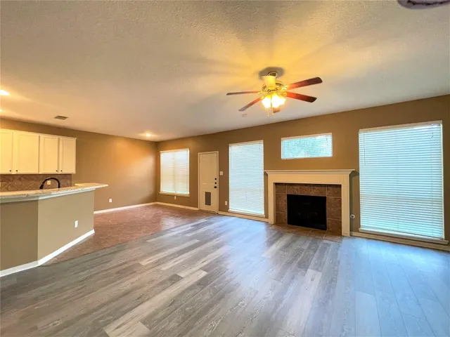 a view of an empty room with wooden floor fireplace and a window