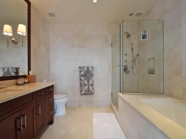 a spacious bathroom with a granite countertop sink a toilet a mirror a shower and a bathtub