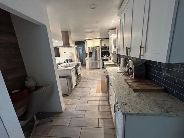 a large kitchen with stainless steel appliances granite countertop a sink stove and cabinets