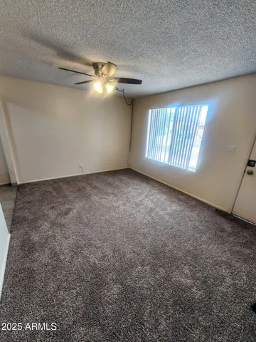 an empty room with windows and ceiling fan