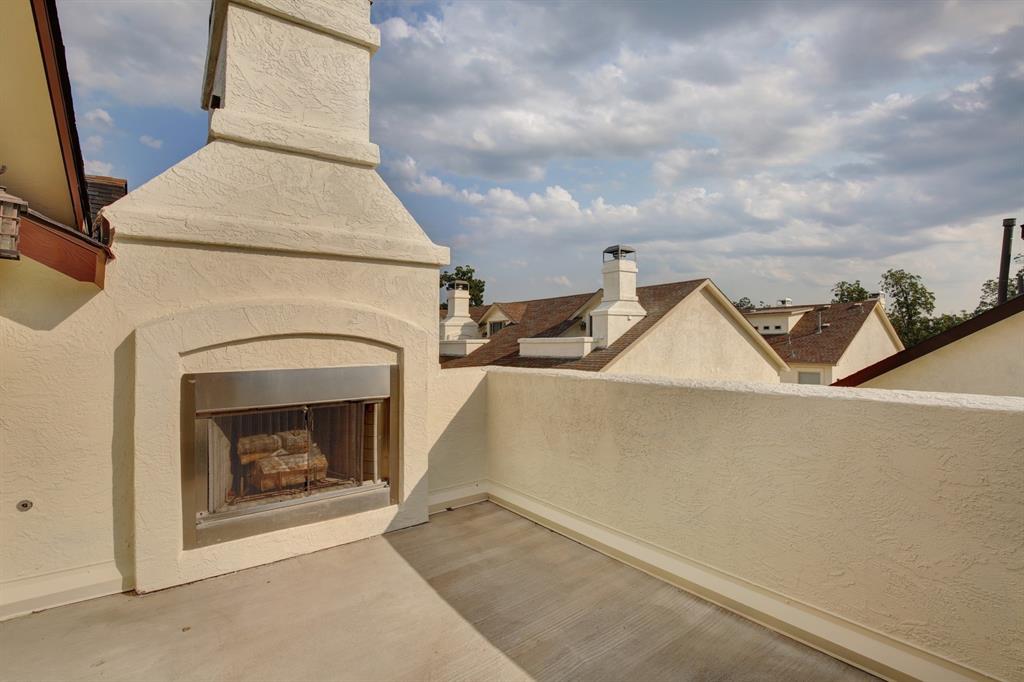 4111 Rawlins Street, Unit 403 Dallas, TX 75219 - Photo 22 of 23 Rooftop patio featuring a stucco fireplace with a stainless steel firebox, stucco parapet walls, and a concrete-finish surface