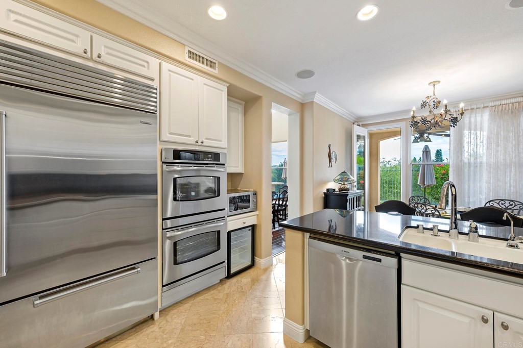 7057 Eider Court Carlsbad, CA 92011 - Photo 21 of 65 a kitchen with kitchen island granite countertop a sink and stainless steel appliances