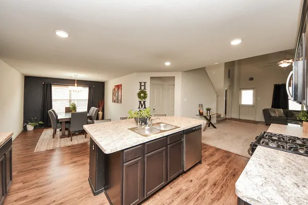 a living room with stainless steel appliances granite countertop furniture and wooden floor