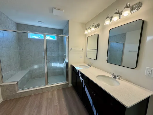 a bathroom with a double vanity sink mirror and shower