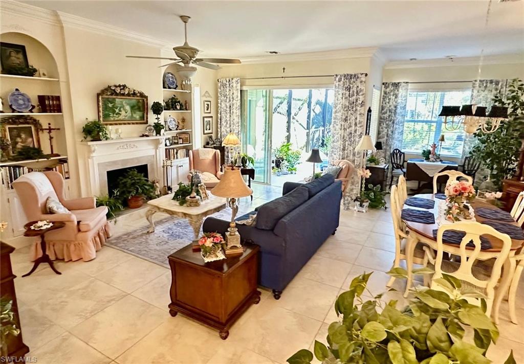 5220 Milano Street Ave Maria, FL 34142 - Photo 16 of 27 Living area featuring built in shelves, crown molding, plenty of natural light, light tile patterned flooring, and a fireplace with flush hearth