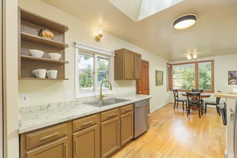 a living room with stainless steel appliances granite countertop a dining table chairs and wooden floor