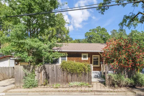 a front view of a house with a yard and tree s