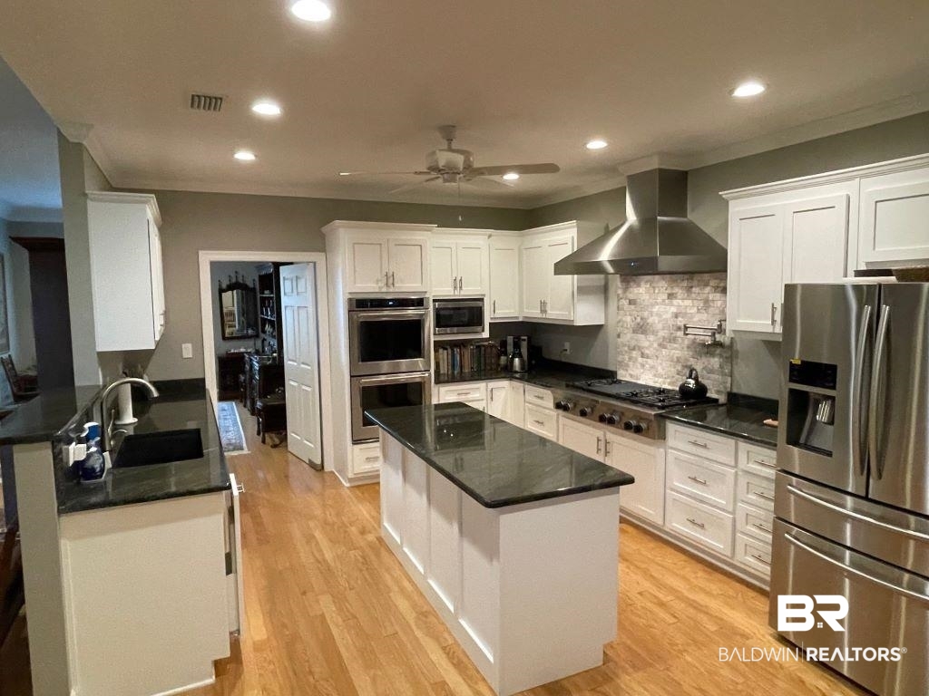 6426 East Quarry Drive Elberta, AL 36530 - Photo 6 of 19 Kitchen featuring appliances with stainless steel finishes, ceiling fan, wall chimney exhaust hood, and white cabinetry