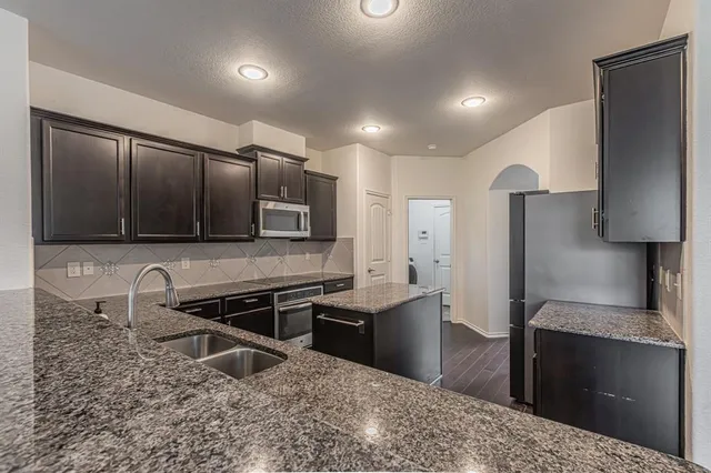 a kitchen with stainless steel appliances kitchen island granite countertop a stove and a sink