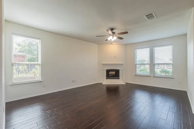 an empty room with wooden floor fireplace and windows