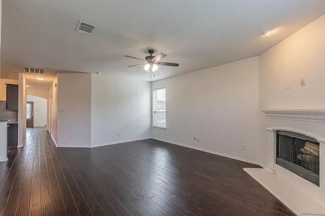a view of an empty room with wooden floor and a fireplace