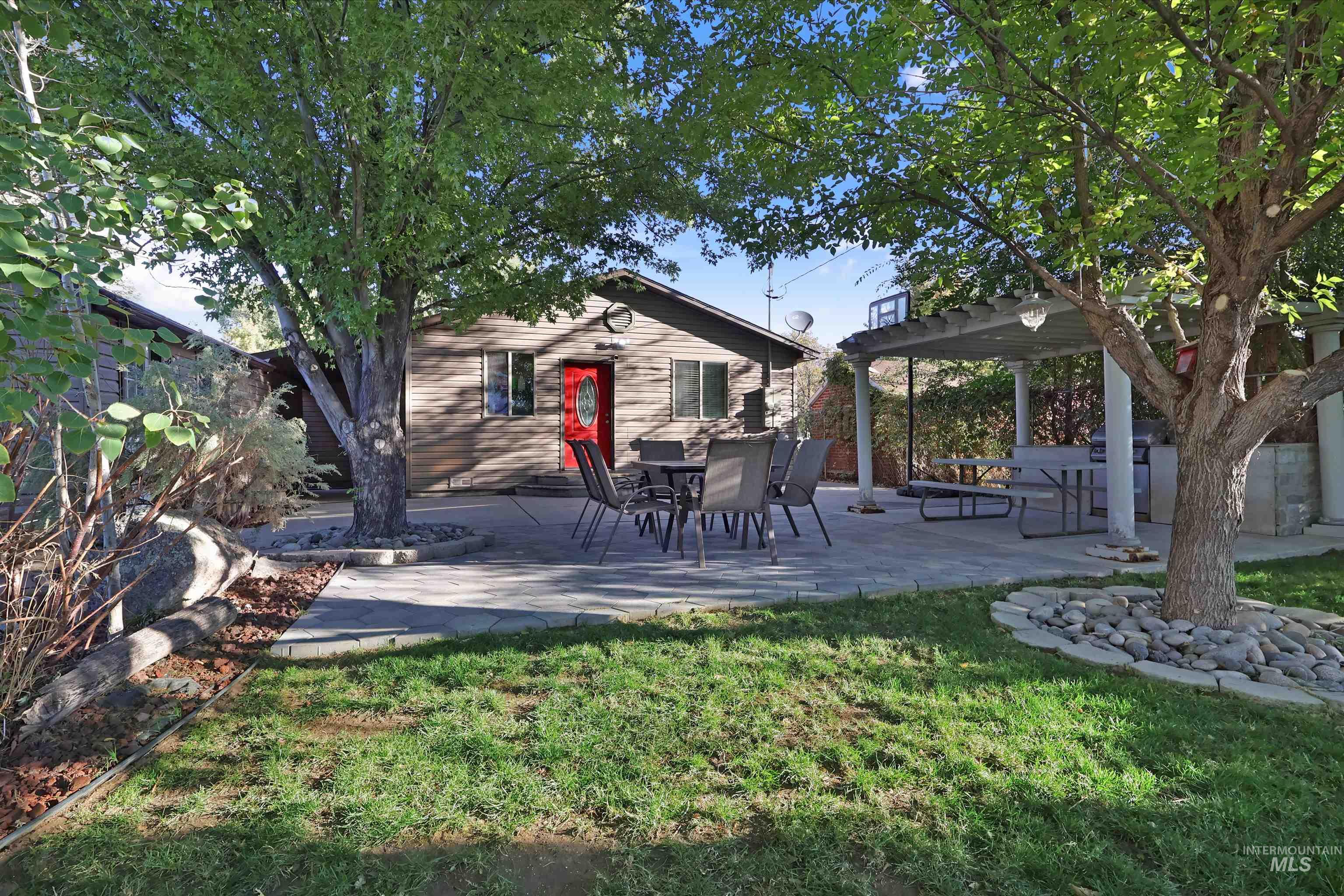 1009 9th Street Rupert, ID 83350 - Photo 27 of 28 Expansive backyard featuring a manicured lawn, established shade trees, and a paved patio area