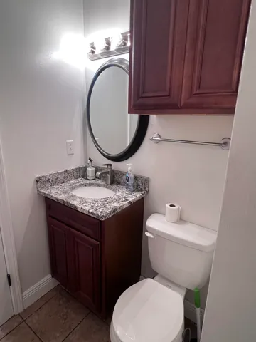 a bathroom with a granite countertop toilet sink and mirror