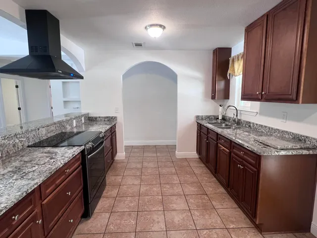 a kitchen with granite countertop a stove top oven microwave and cabinets