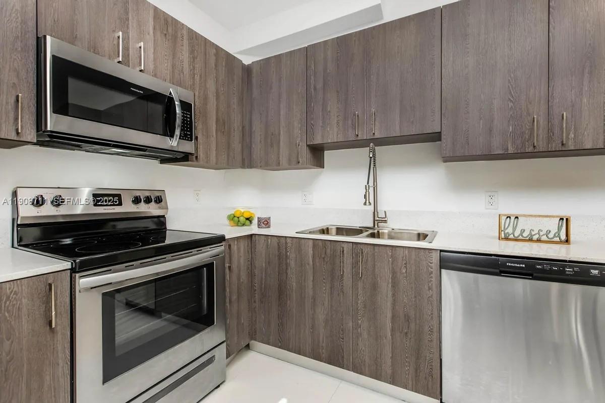 25850 Southwest 140th Court, Unit 6209 Homestead, FL 33032 - Photo 6 of 29 a kitchen with stainless steel appliances a stove a microwave sink and cabinets
