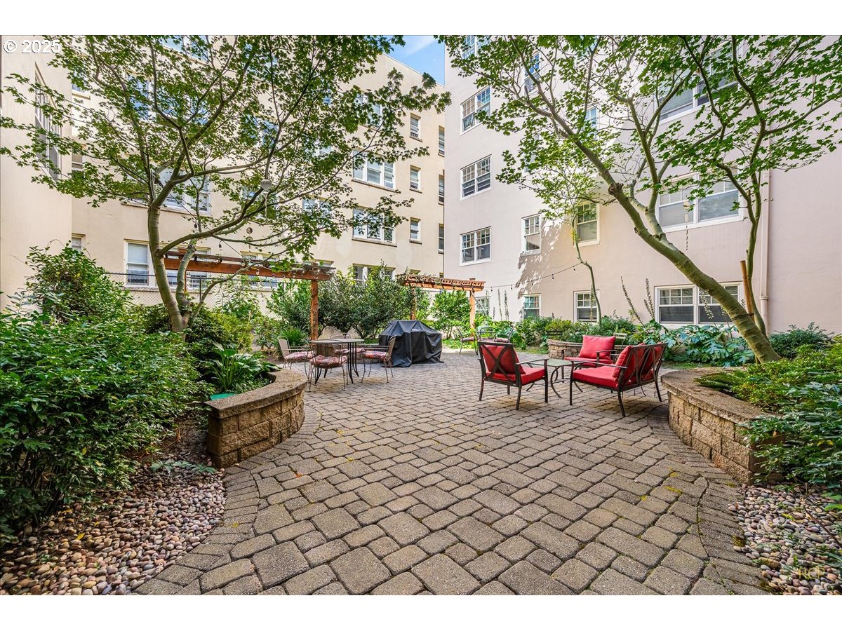 2015 Northwest Flanders Street, Unit 408 Portland, OR 97209 - Photo 22 of 37 a view of a patio with table and chairs potted plants and large tree