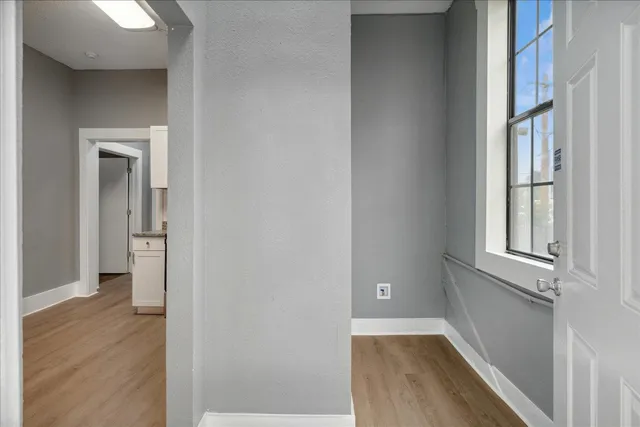 a view of an empty room with wooden floor and a window