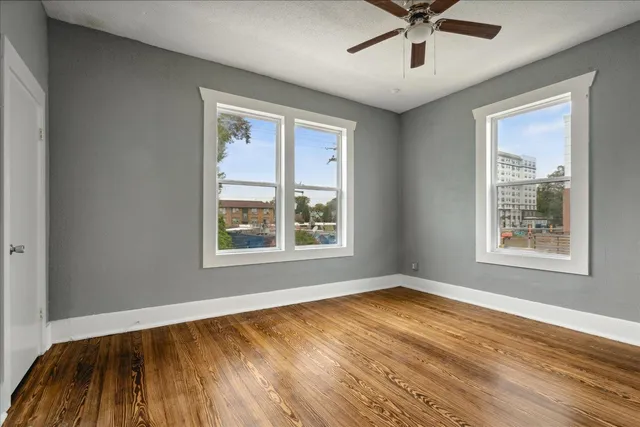 a view of an empty room with a window and wooden floor