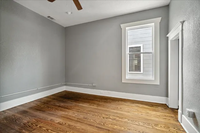 a view of empty room with wooden floor and fan