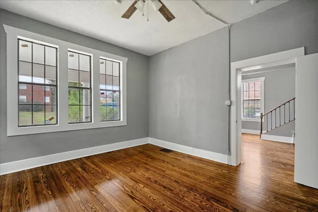 a view of empty room with wooden floor and fan