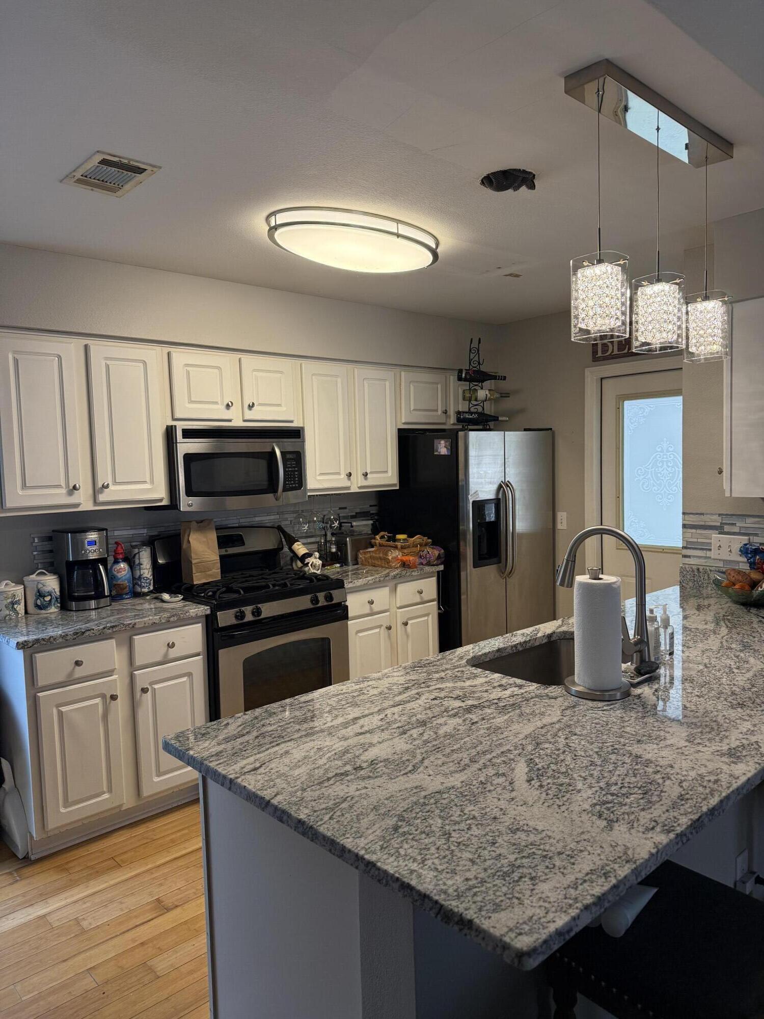 3863 Indian Trail, Unit 106 Destin, FL 32541 - Photo 9 of 22 a kitchen with kitchen island granite countertop a sink cabinets and stainless steel appliances