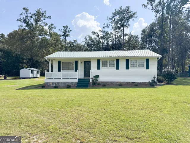 a front view of house with yard and trees in the background