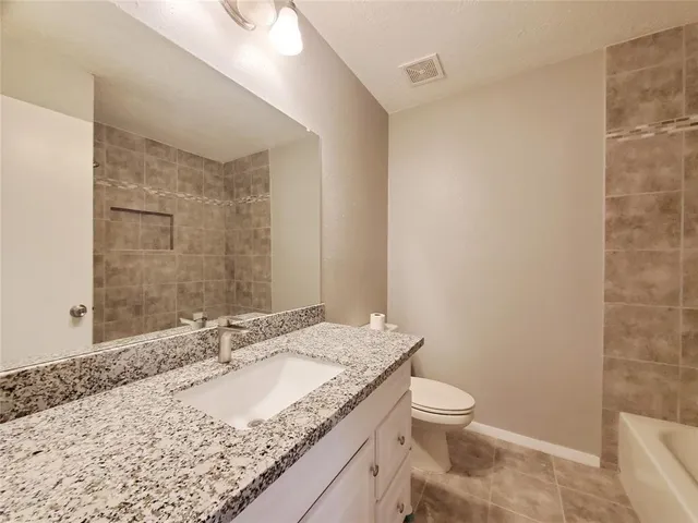 a bathroom with a granite countertop sink a toilet and a mirror