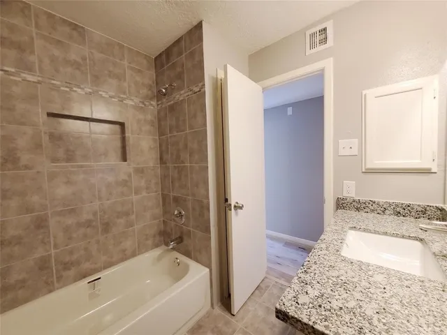 a bathroom with a granite countertop bathtub shower and vanity