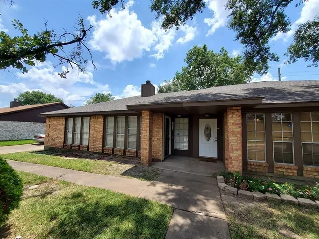 a view of a house with a yard plants and large tree