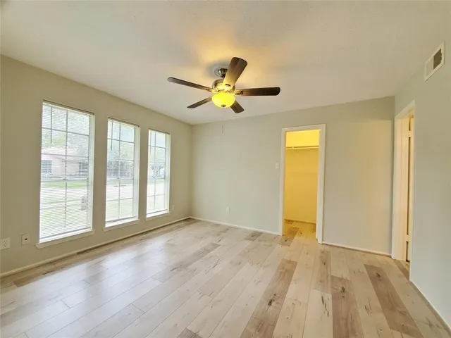 a view of an empty room with window and wooden floor