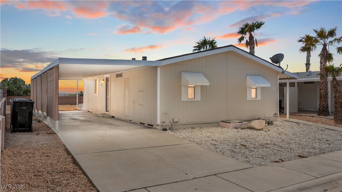 Property exterior at dusk with driveway and an attached carport