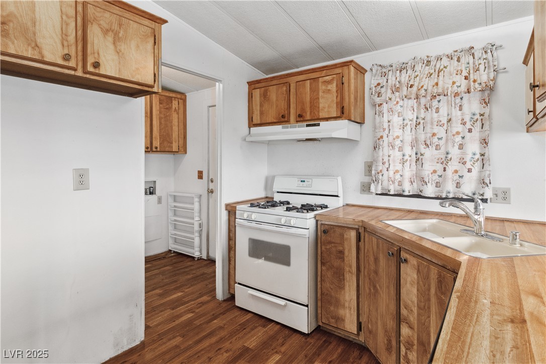 1671 Granada Street Laughlin, NV 89029 - Photo 14 of 63 Kitchen with dark wood-type flooring, light countertops, white gas stove, under cabinet range hood, and a sink