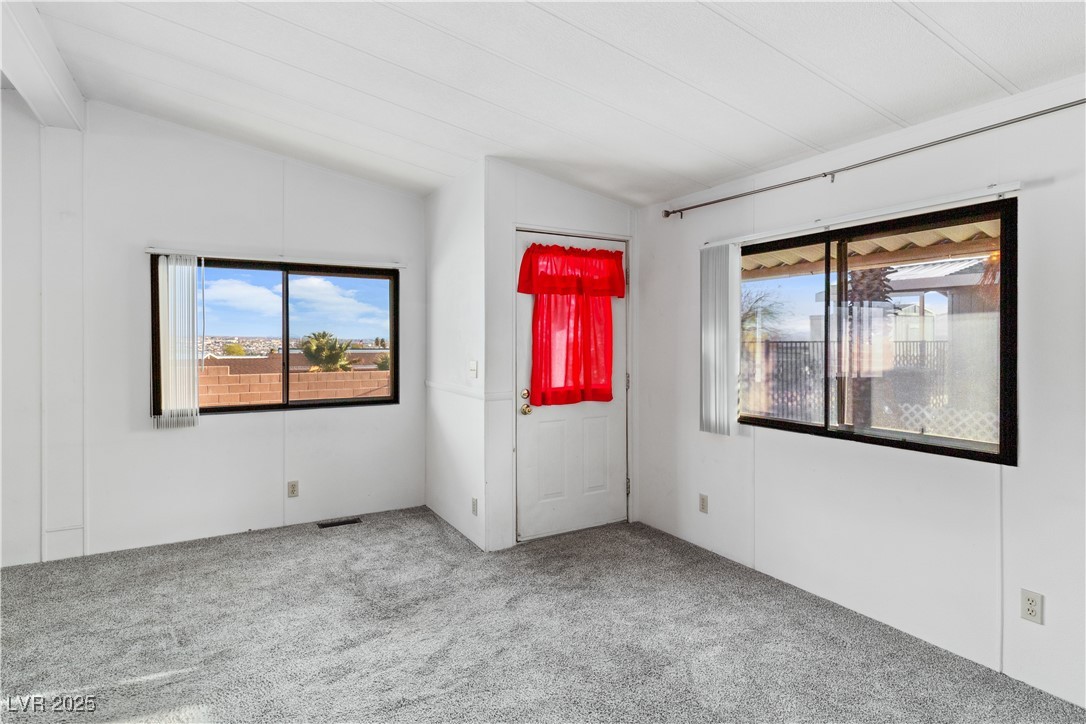 1671 Granada Street Laughlin, NV 89029 - Photo 6 of 63 Carpeted living room featuring lofted ceiling, visible vents, and a healthy amount of sunlight