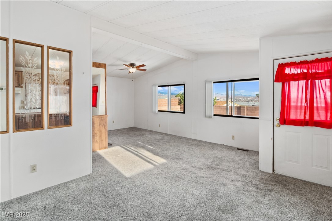 1671 Granada Street Laughlin, NV 89029 - Photo 7 of 63 Carpeted living room featuring lofted ceiling, visible vents, and a healthy amount of sunlight