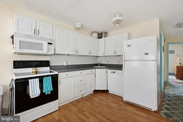 a kitchen with granite countertop white cabinets and refrigerator