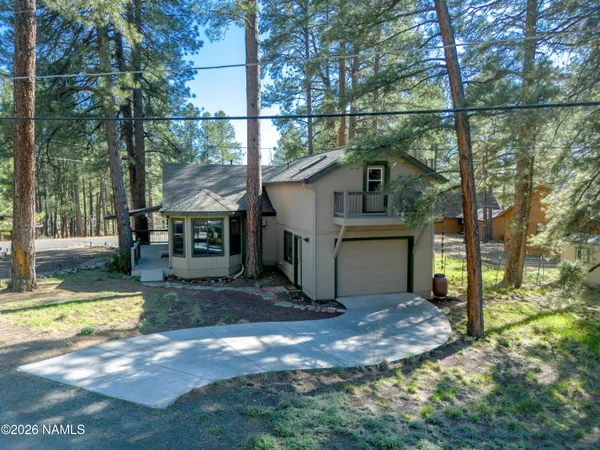 a view of a small house with a big yard and large tree