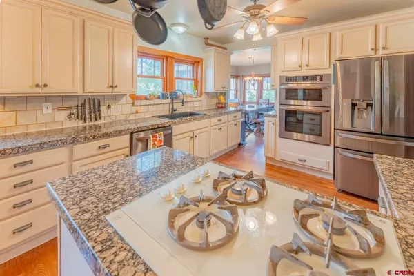 a kitchen with stainless steel appliances granite countertop a sink a stove and a wooden cabinets