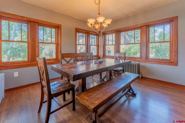 a dining room with wooden floor a chandelier a wooden table and chairs