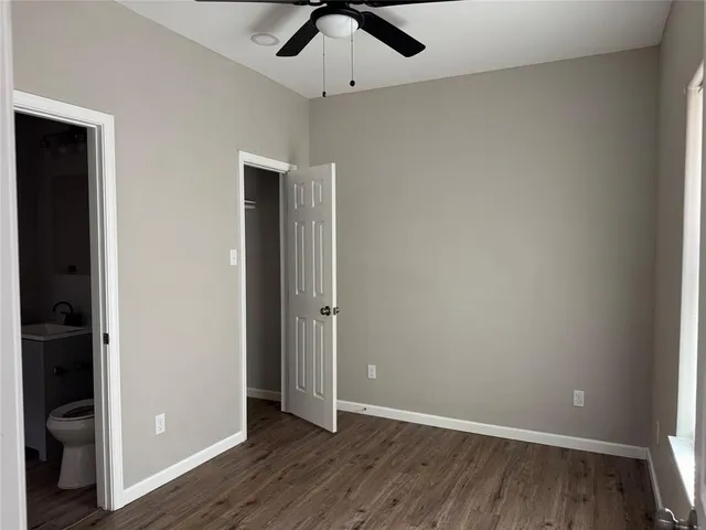 an empty room with wooden floor and a ceiling fan
