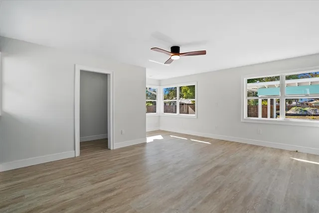 an empty room with wooden floor chandelier and windows