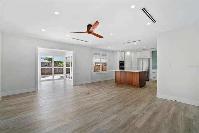 a view of an empty room with wooden floor and windows