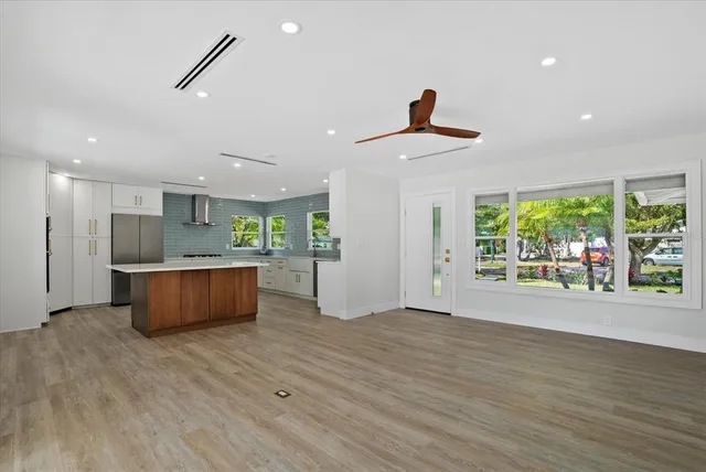 a view of kitchen with stainless steel appliances granite countertop a stove a sink a refrigerator and a wooden floors