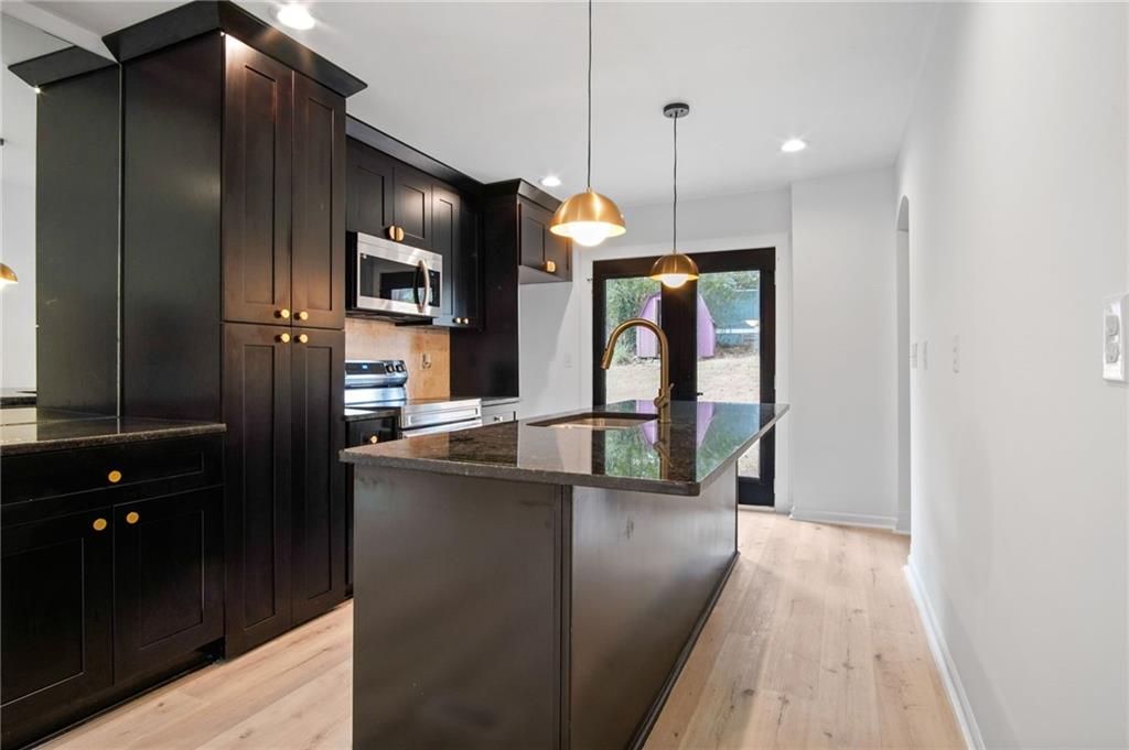 2327 El Paso Road Southwest Atlanta, GA 30331 - Photo 9 of 35 a kitchen with stainless steel appliances kitchen island granite countertop a refrigerator a stove and a wooden floors