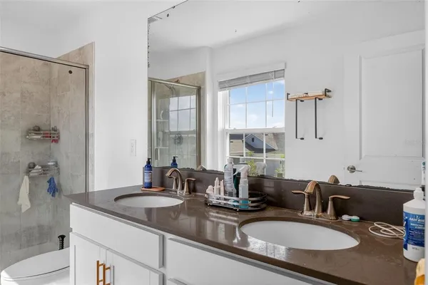 a bathroom with double vanity sinks a mirror and a shower